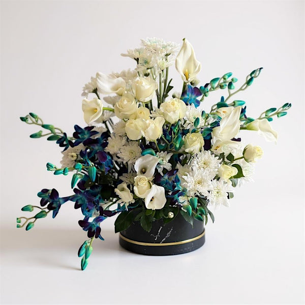 Flower arrangement with white ivory and blue indigo flowers in a box