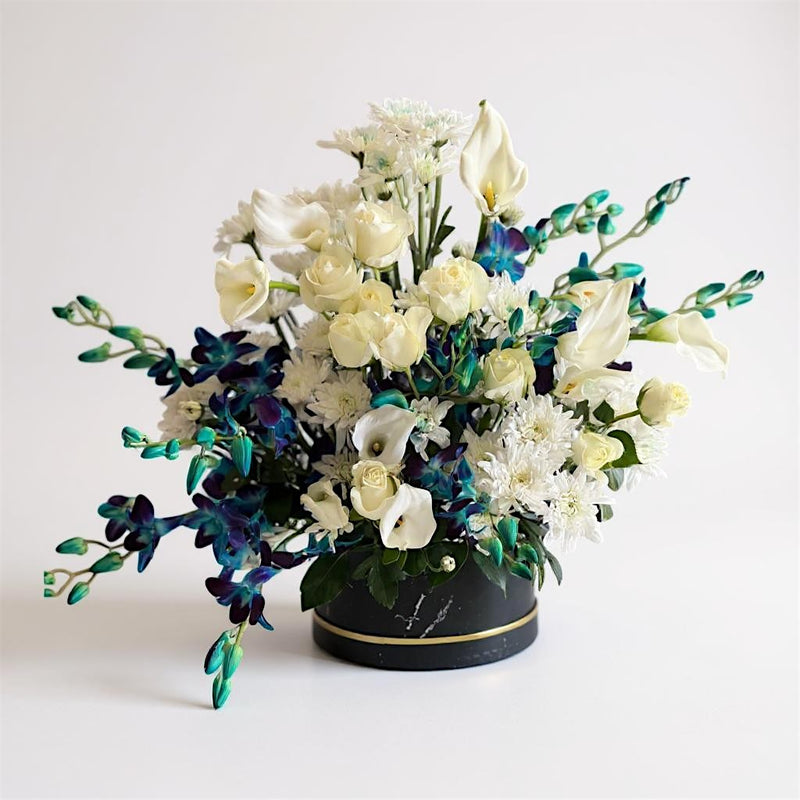 Flower arrangement with white ivory and blue indigo flowers in a box